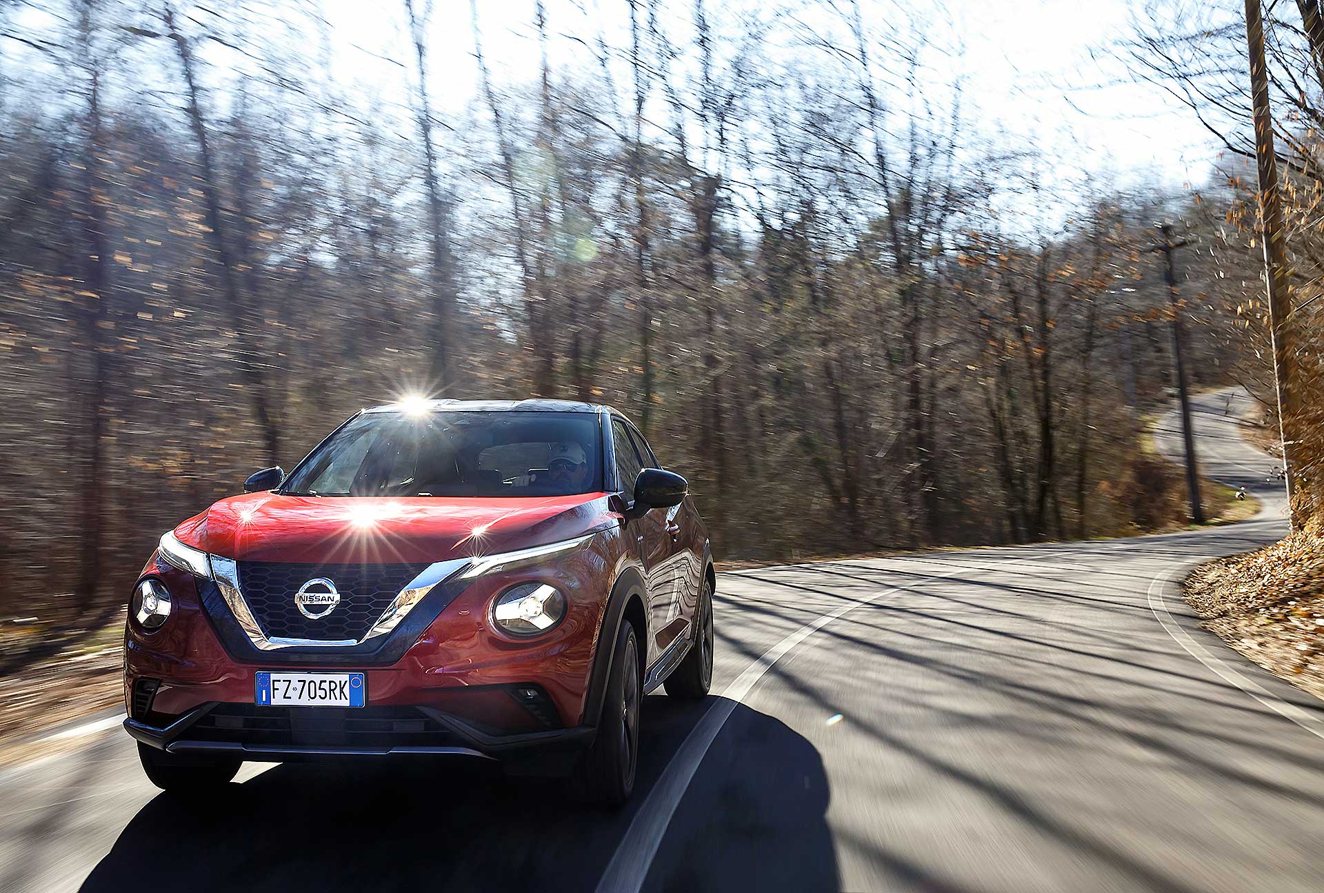 Nissan Juke 2020 arancione in movimento su strada nel bosco